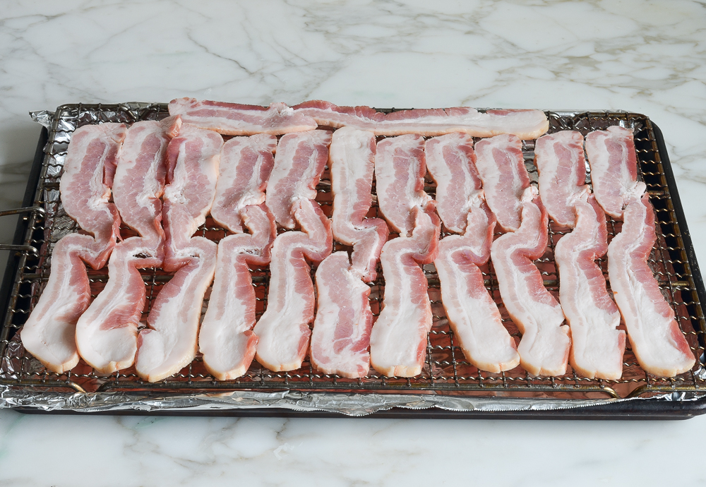 bacon disposé sur une grille et une plaque à pâtisserie