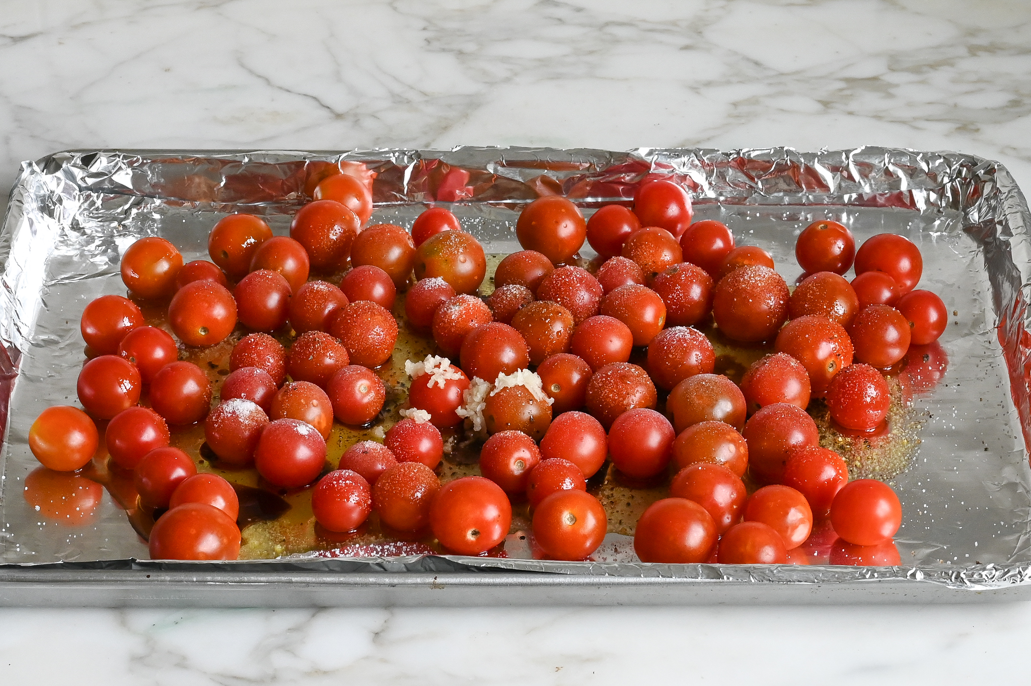 tomates, huile, vinaigre, ail et assaisonnement sur une plaque à pâtisserie
