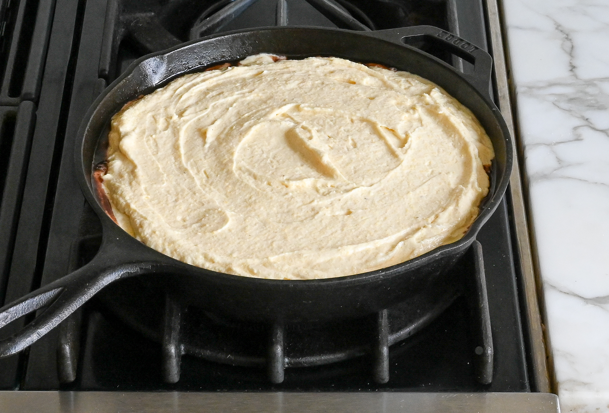 pâte à gâteau étalée sur des cerises dans une poêle